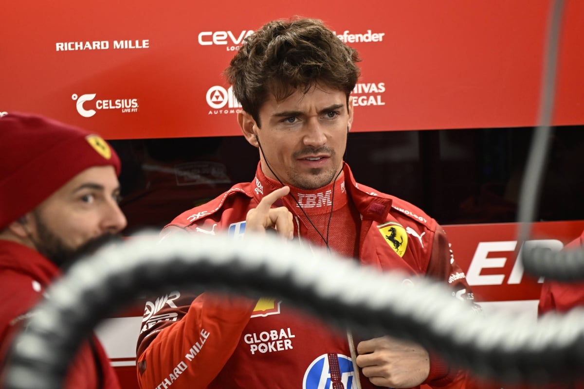 charles leclerc in the Ferrari garage looking annoyed
