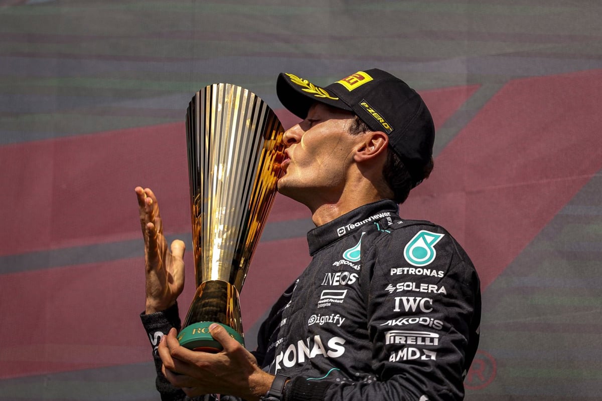 George Russell kisses a trophy on the F1 podium
