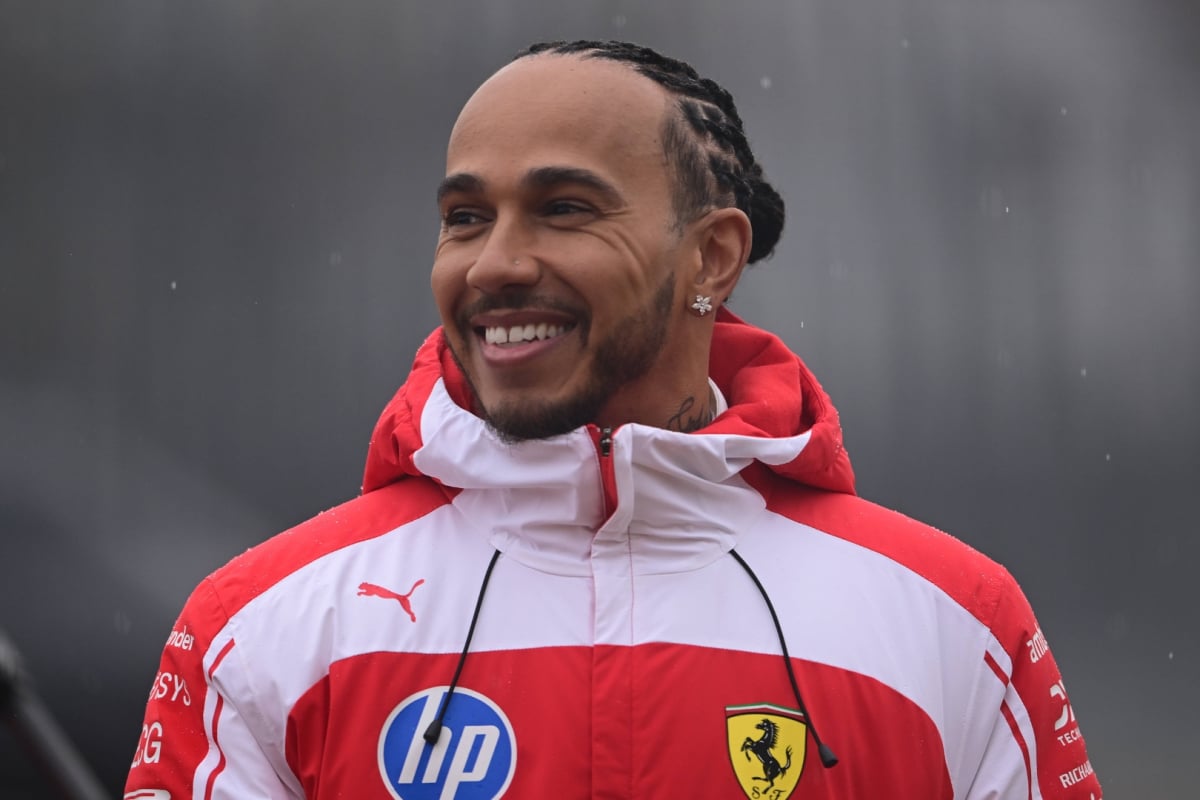 Lewis Hamilton smiling from ear to ear in 2026 red and white Ferrari F1 windbreaker
